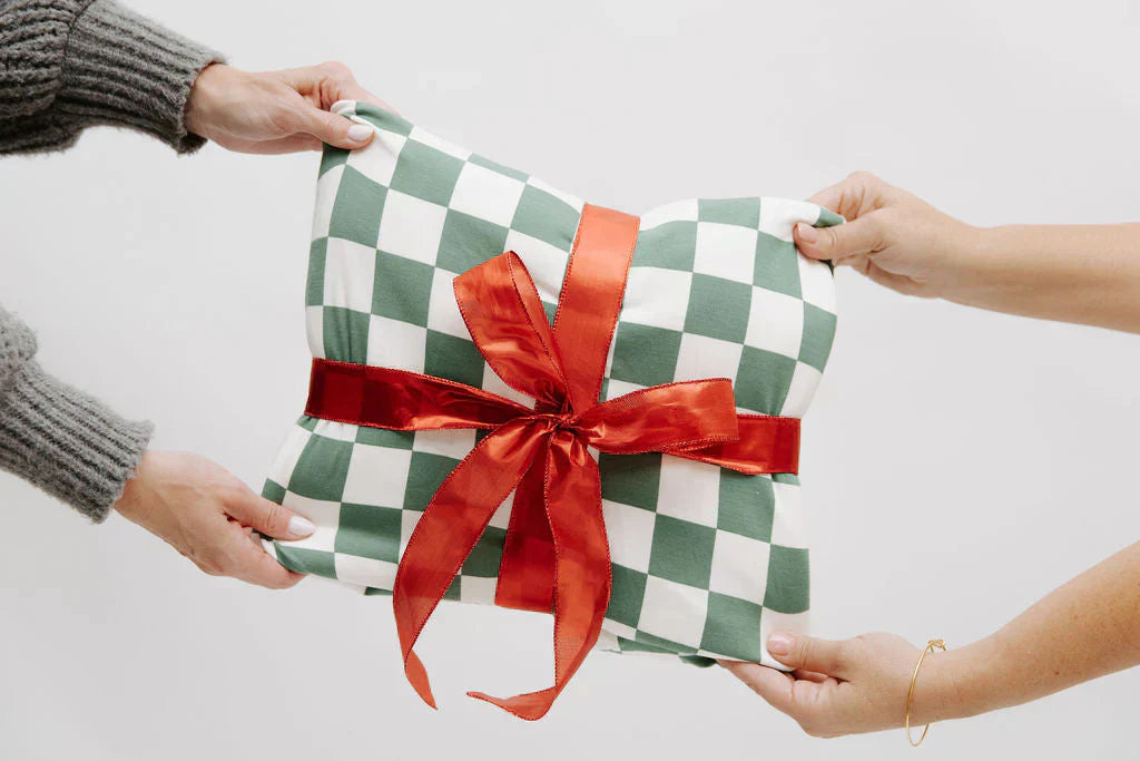 
      A green and white checked blanket wrapped in a red bow being passed to someone.
    