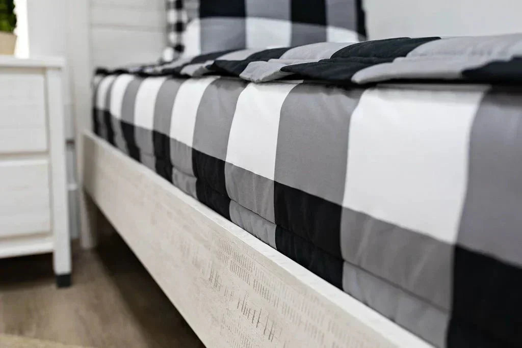 
      A low side shot of a bed made with black and white checked zipper bedding.
    