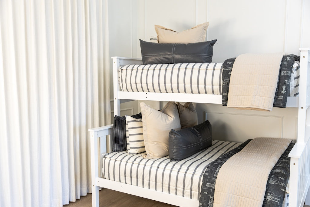 A bunk bed made with white and gray striped zipper bedding with neutral accessories.