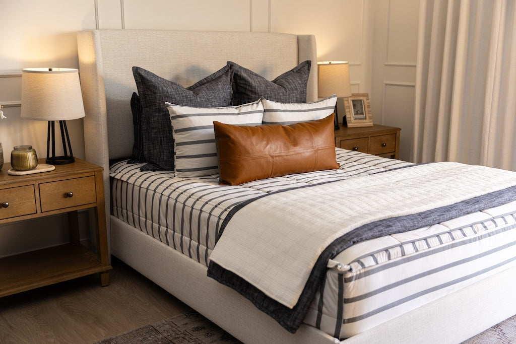 A white and gray striped zipper bedding with neutral accessories.