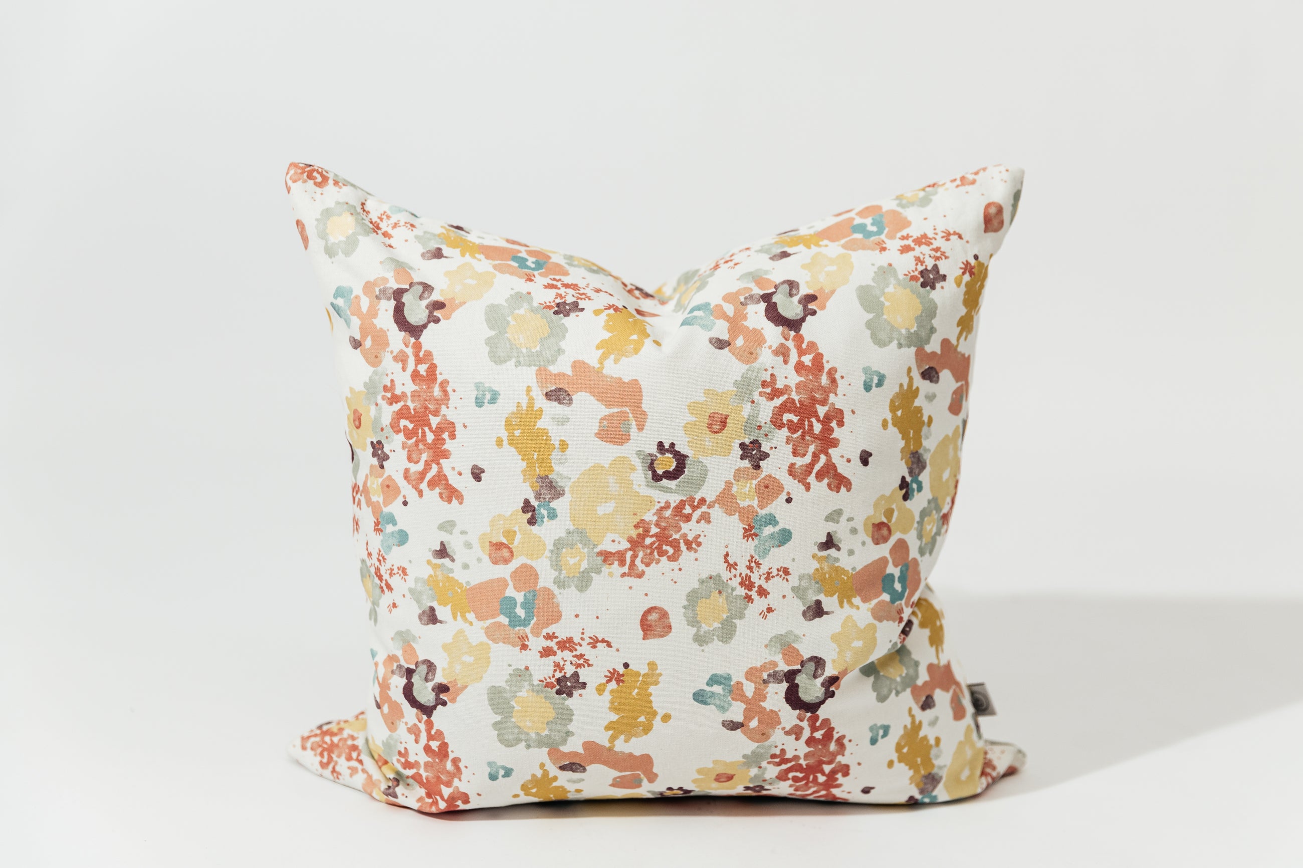A floral throw pillow with a white backdrop.
