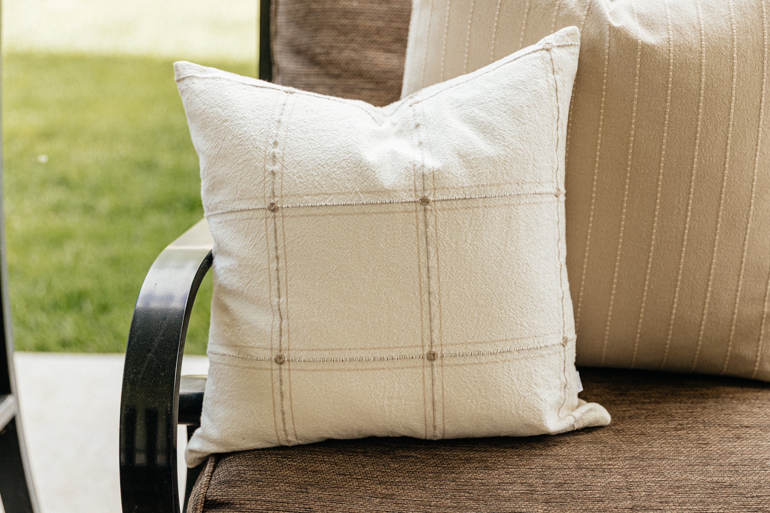 A close up of a plaid pillow cover on an outdoor chair.