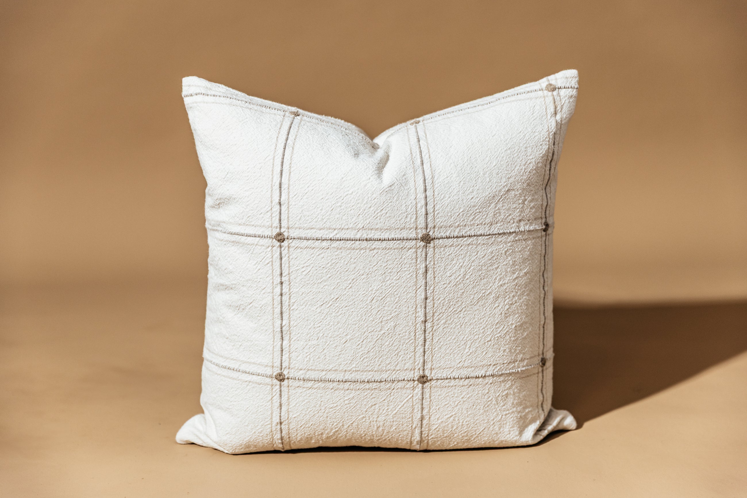 A plaid pillow cover on a brown backdrop.