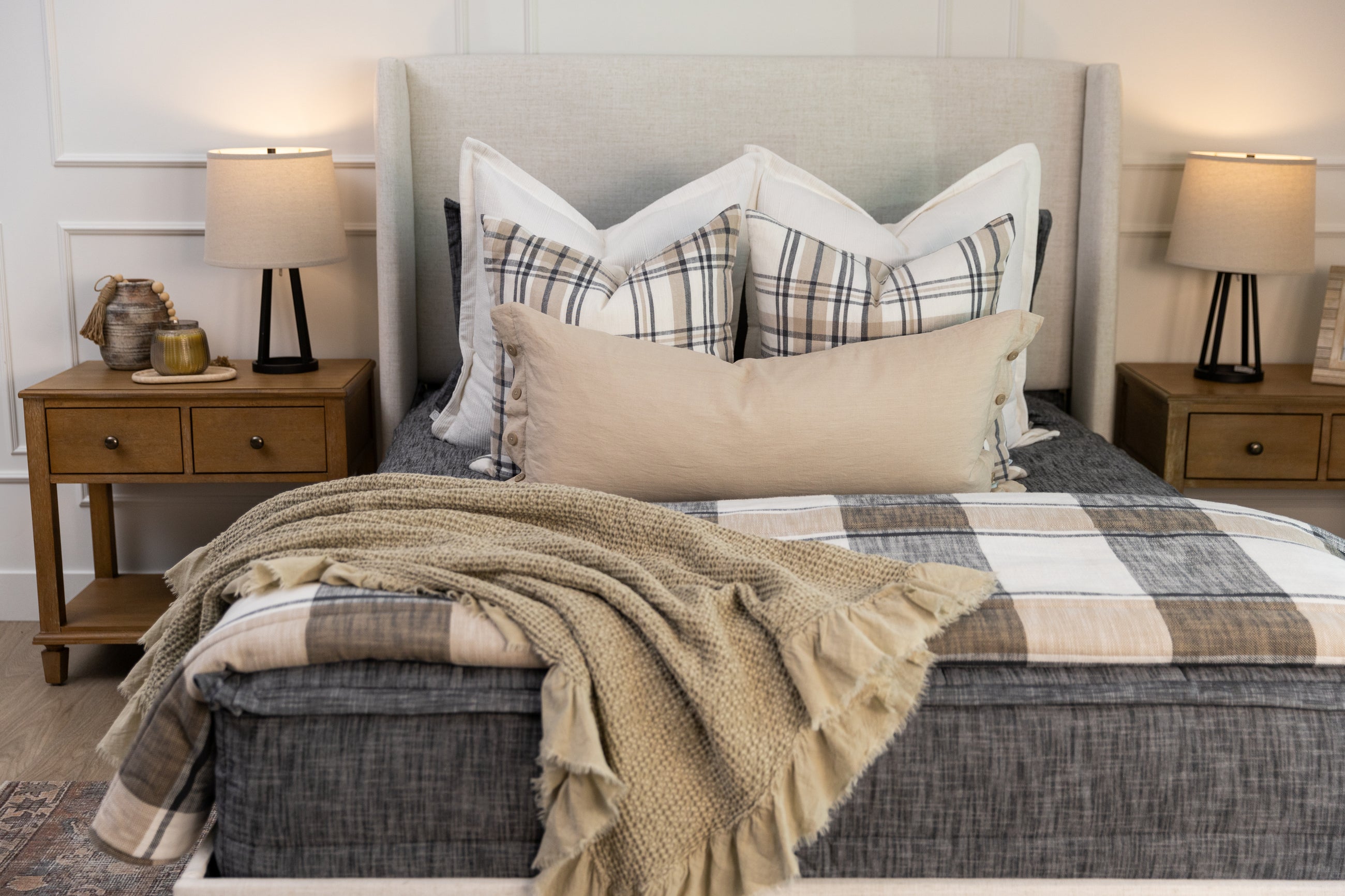 A dark gray beddys set with plaid bedding accessories and a linen pillow.