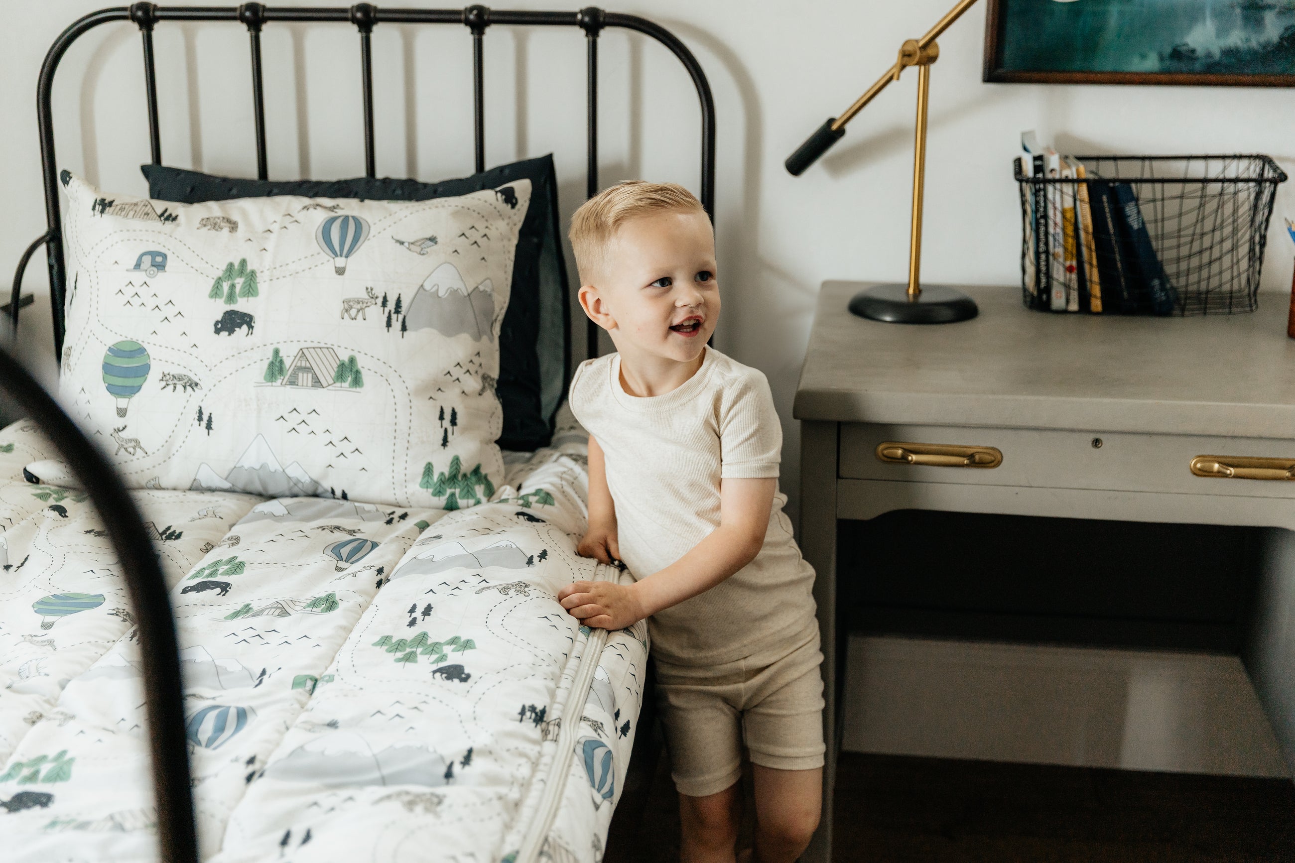 A boy zipping a bed made with outdoor themed zipper bedding.