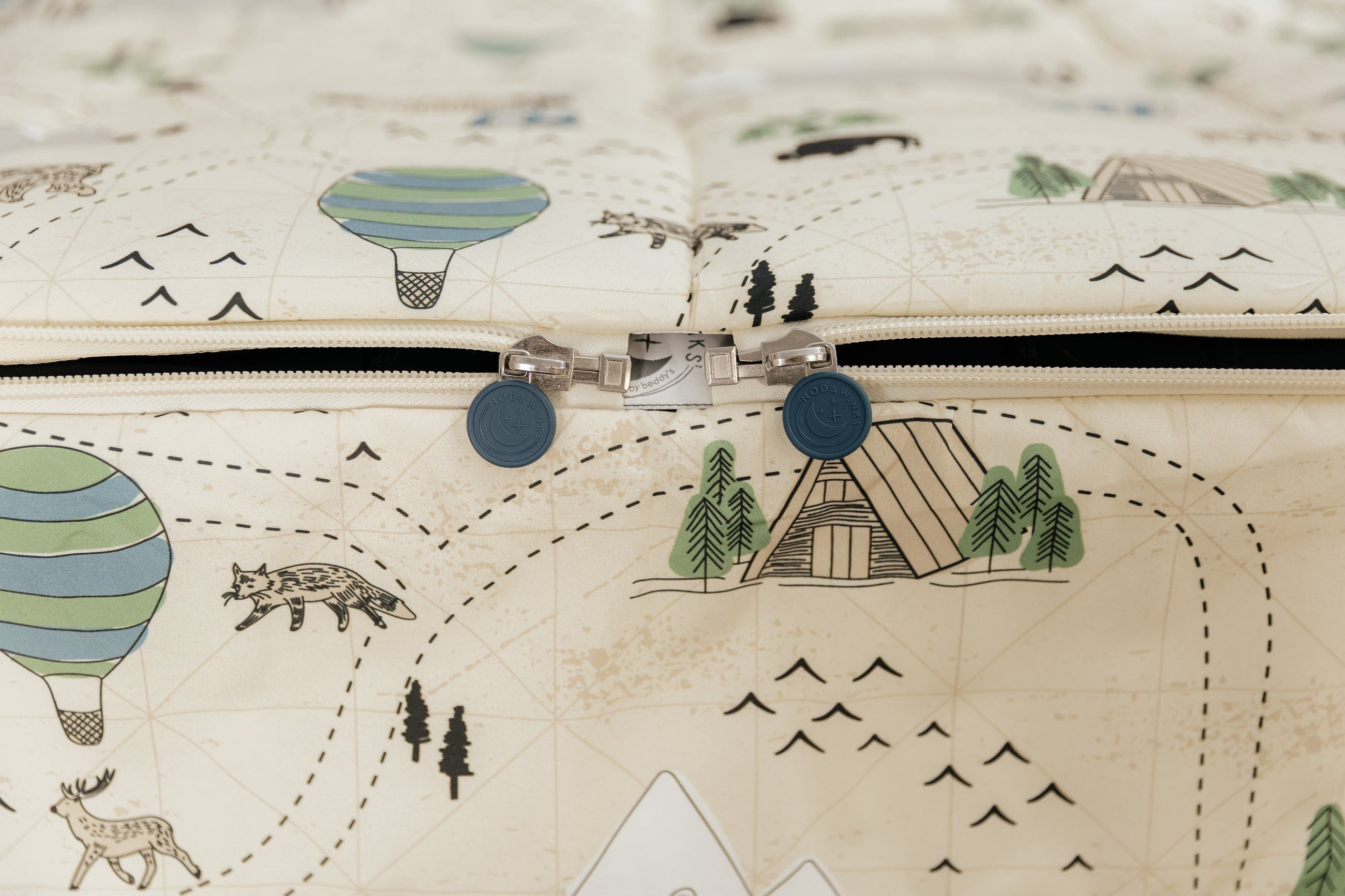 A bed made with outdoor themed zipper bedding, the zippers completely unzipped to the foot of the bed.