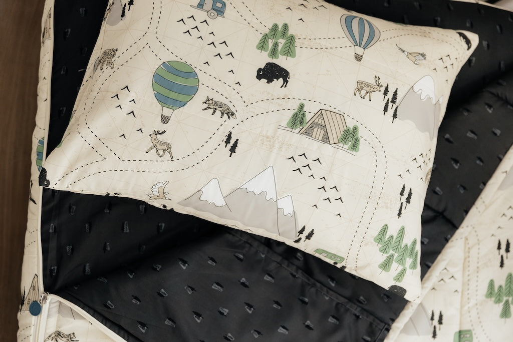 An outdoor print kids zipper bedding set with the top unzipped and pulled back to show the interior design and the pillow tossed on top of the bed.