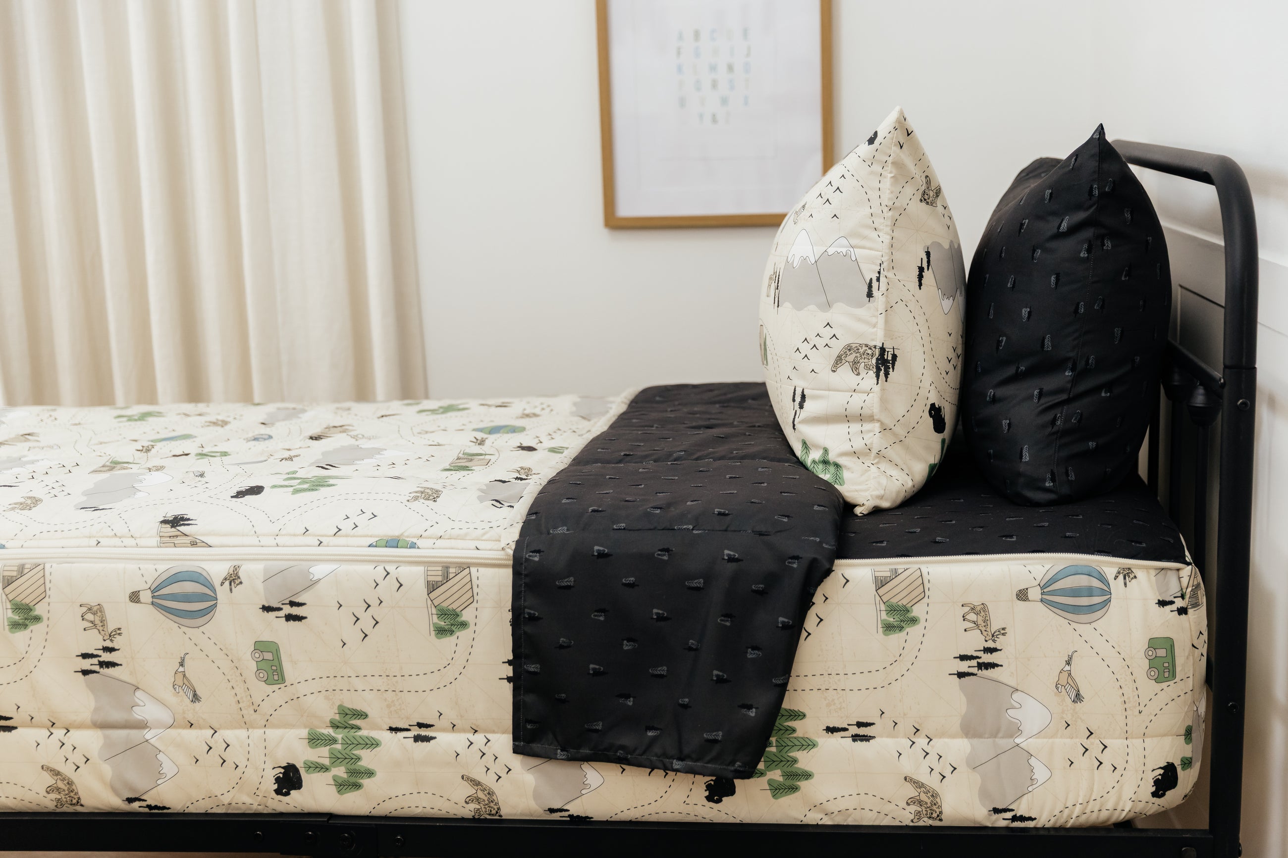 A bed made with outdoor themed zipper bedding, showcasing the pillowcase and sham, the top of the bedding unzipped and pulled back.