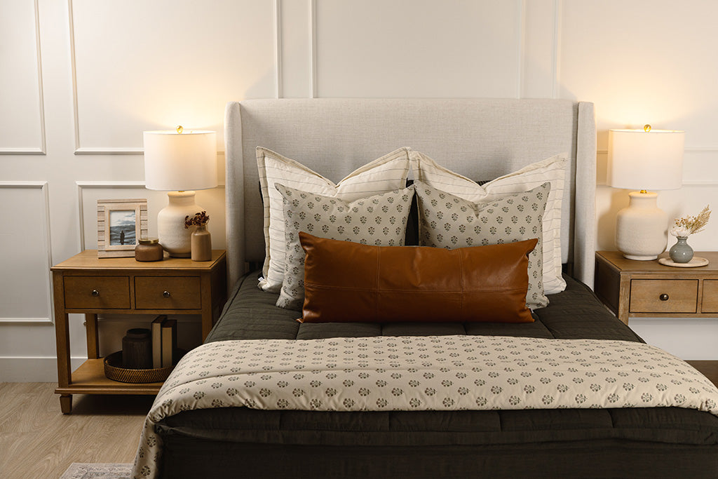 Black knit bedding with white, floral, and leather accessories. 