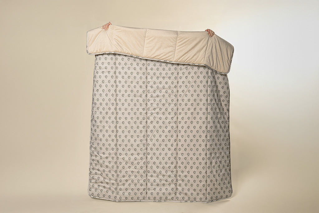 A tan, pink, and green blockprint floral  with cream corduroy minky blanket on a paper backdrop