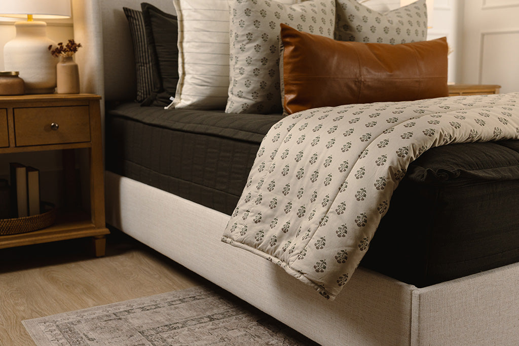 A black knit bed made with white, floral, and leather accessories. 