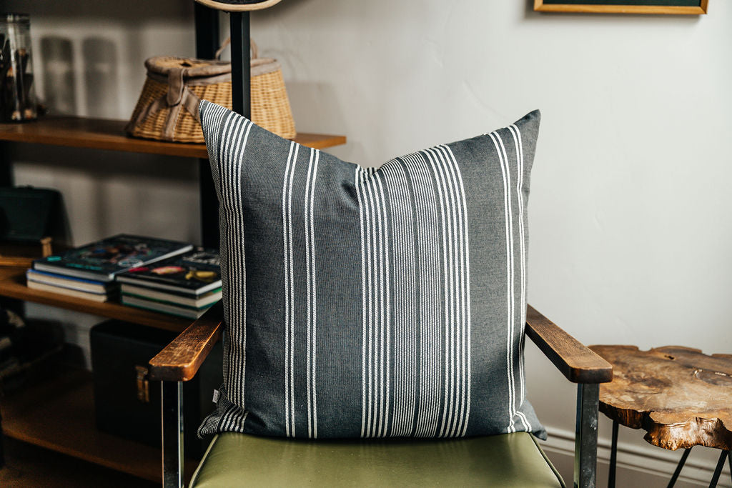 A woven dark gray and white striped euro pillow arranged on a green chair in an office.