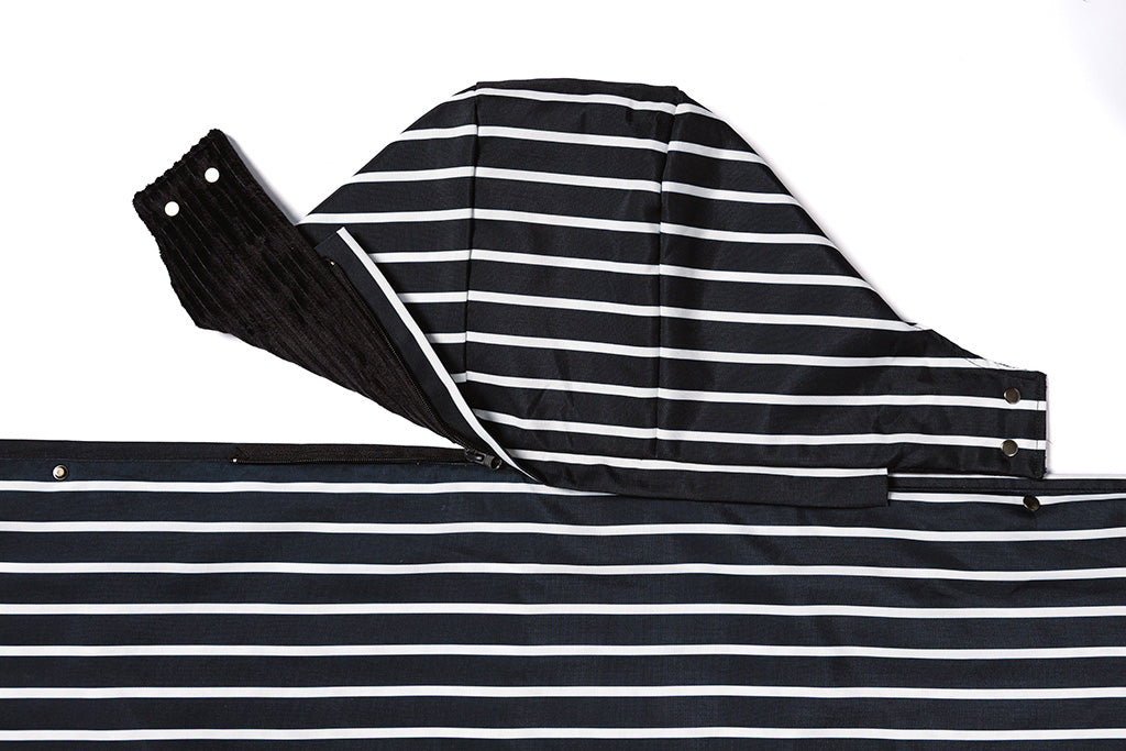A black and white striped blanket with an attachable hood on a white backdrop.