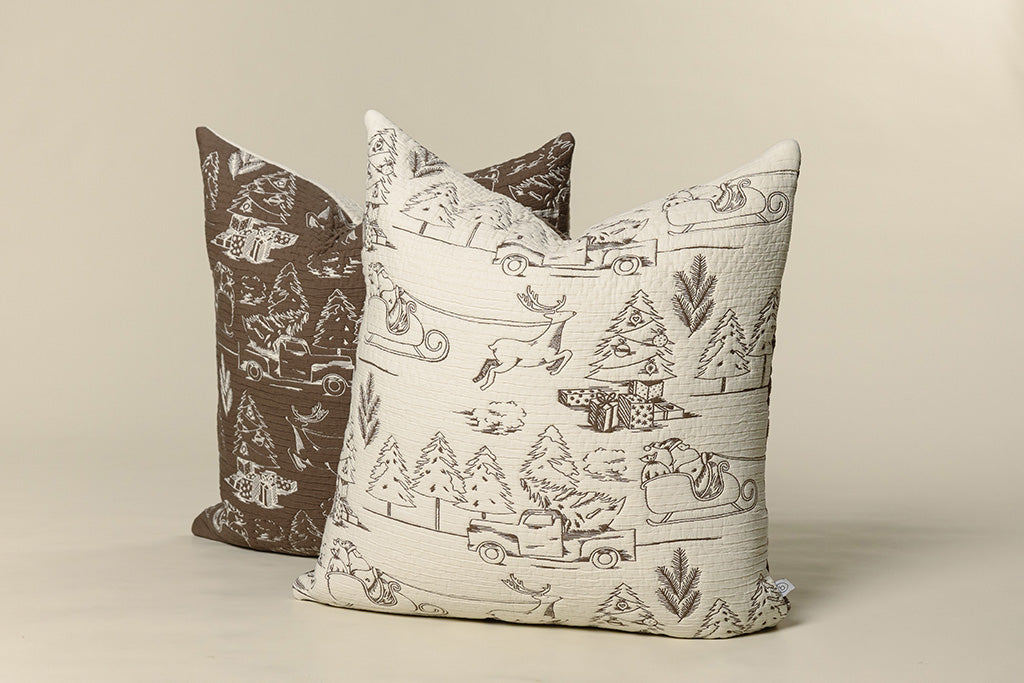 Brown and cream quilted holiday themed pillows on a paper backdrop.