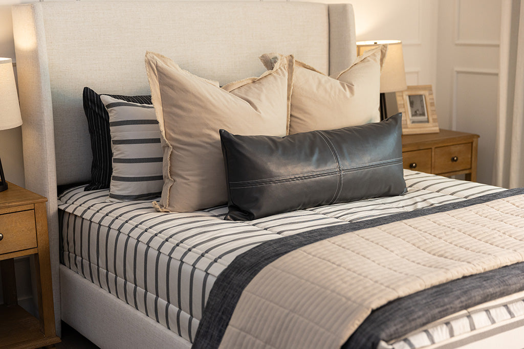 A queen bed made with white and black striped zipper bedding paired with neutral and black accessories.