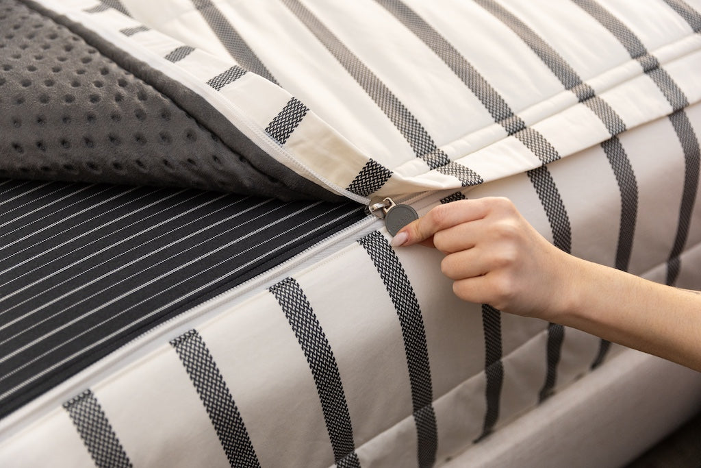 A close up view of the zipper function on white and black striped zipper bedding.