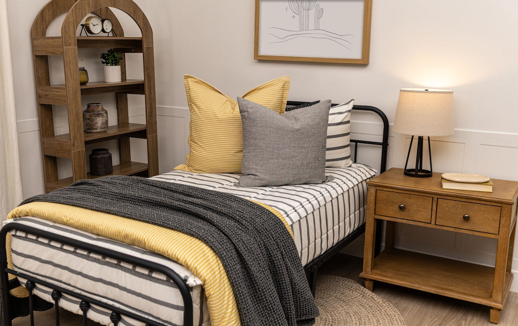 Twin bed with white and gray stripe zipper bedding with neutral accessories.	