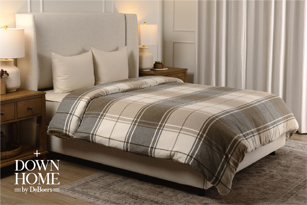 A brown, gray, and white plaid duvet on cream sheets on a bed.