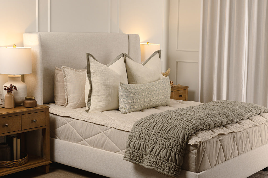 Striped, quilted, tan zipper bedding with cream, floral, and green accessories. 