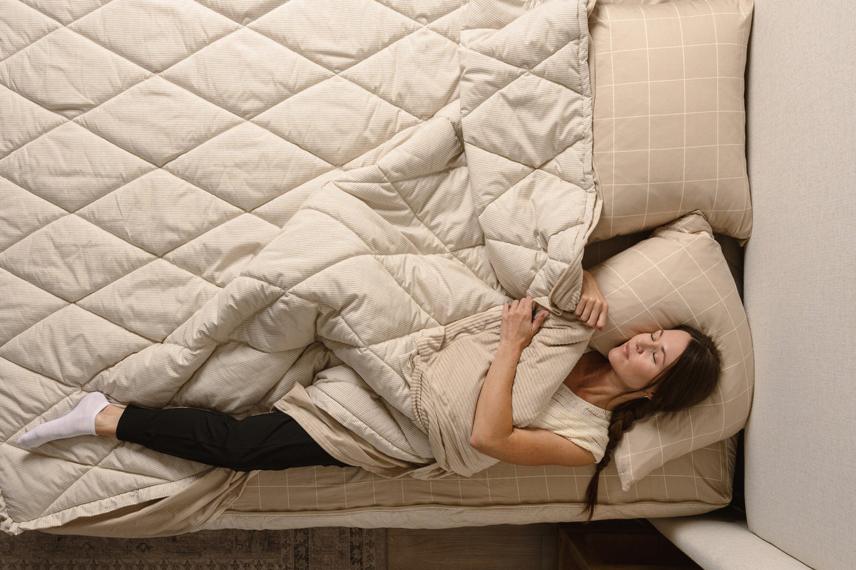 A woman sleeping in her tan stripe quilted zipper bedding. 