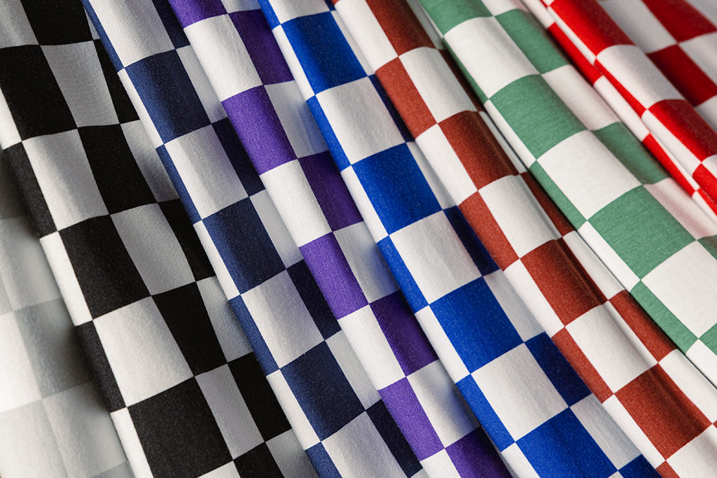 Different colored check blankets laying on top of each other. 