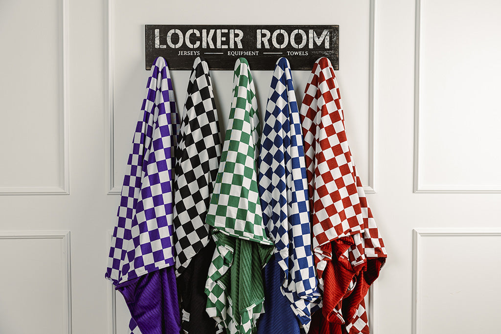 Different colored check blankets hanging on a decorative wall hooks on a white backdrop.
