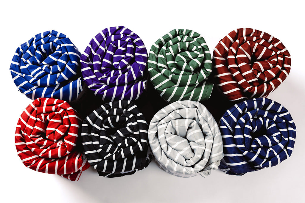 Different colored stipe blankets rolled up on a white backdrop.