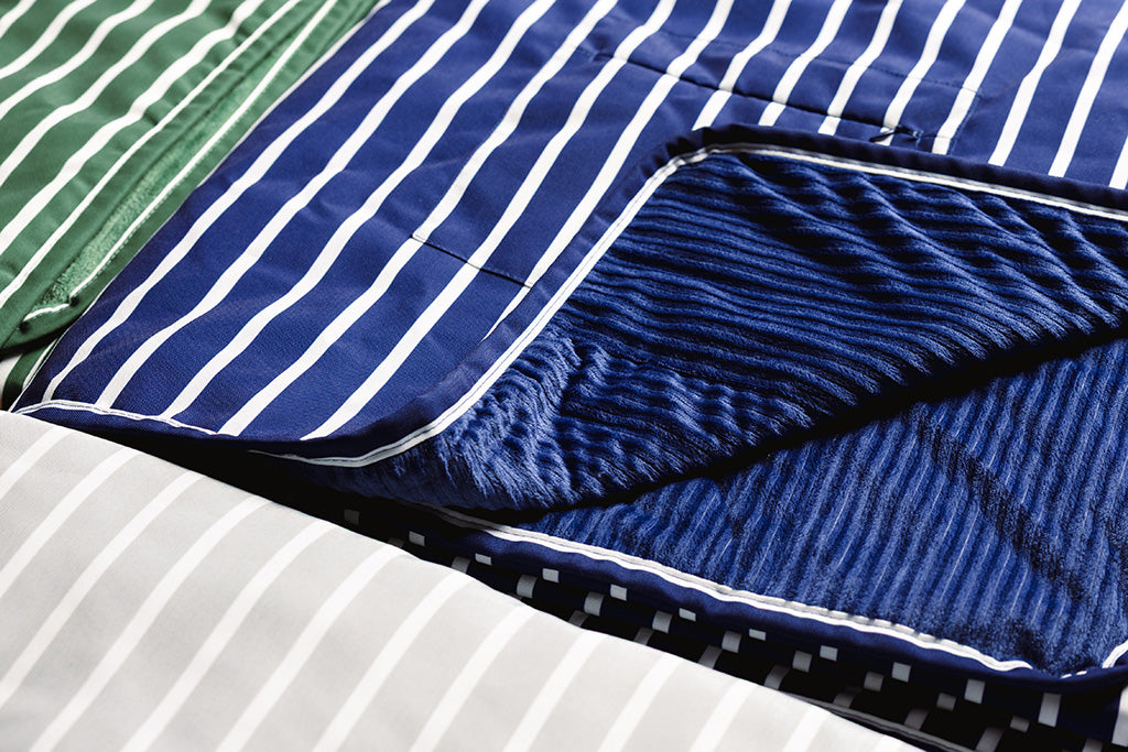 A green, grey, and navy white striped blanket with a minky interior. 