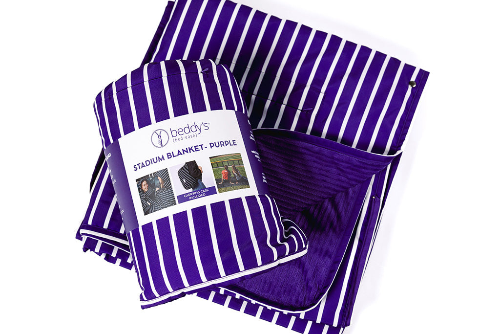 A purple and white striped blanket folded and rolled up on a white backdrop.