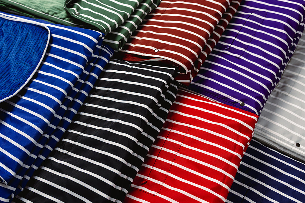 Different colored striped blankets folded and placed next to each other on the floor.