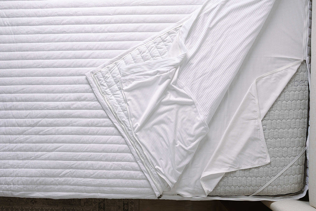 Overhead shot of white quilt stripe texture zipper bedding layers.