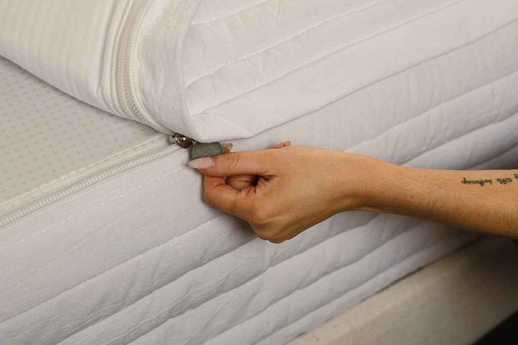Close up photo of zipper being pulled on white stripe quilt zipper bedding.