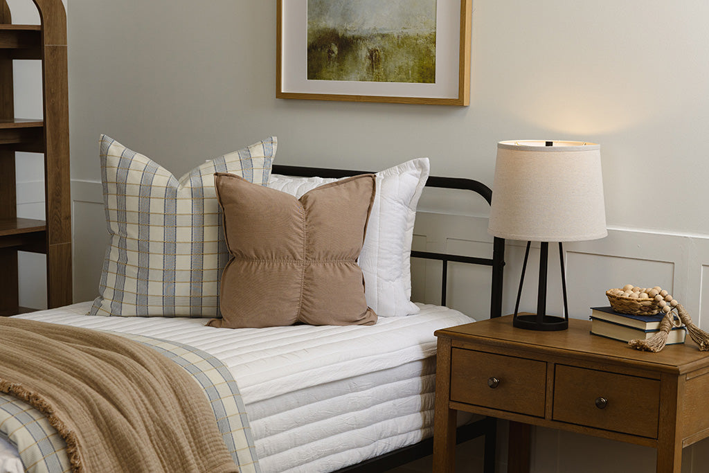 Twin bed with white stripe quilt zipper bedding with plaid and tan accessories.