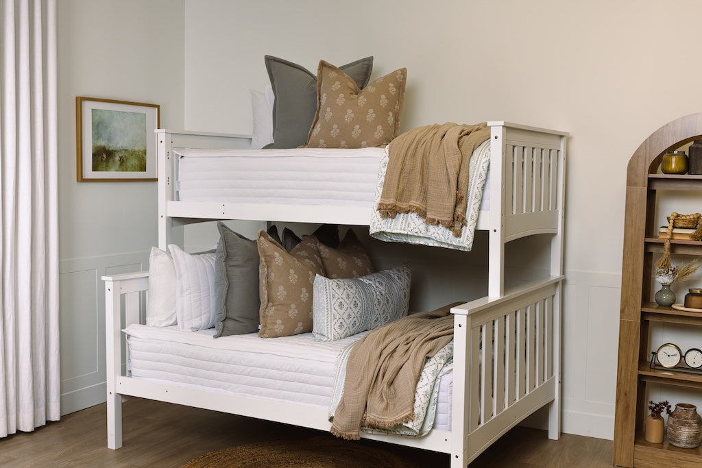 A bunk bed made with tan, gray, and floral accessories.