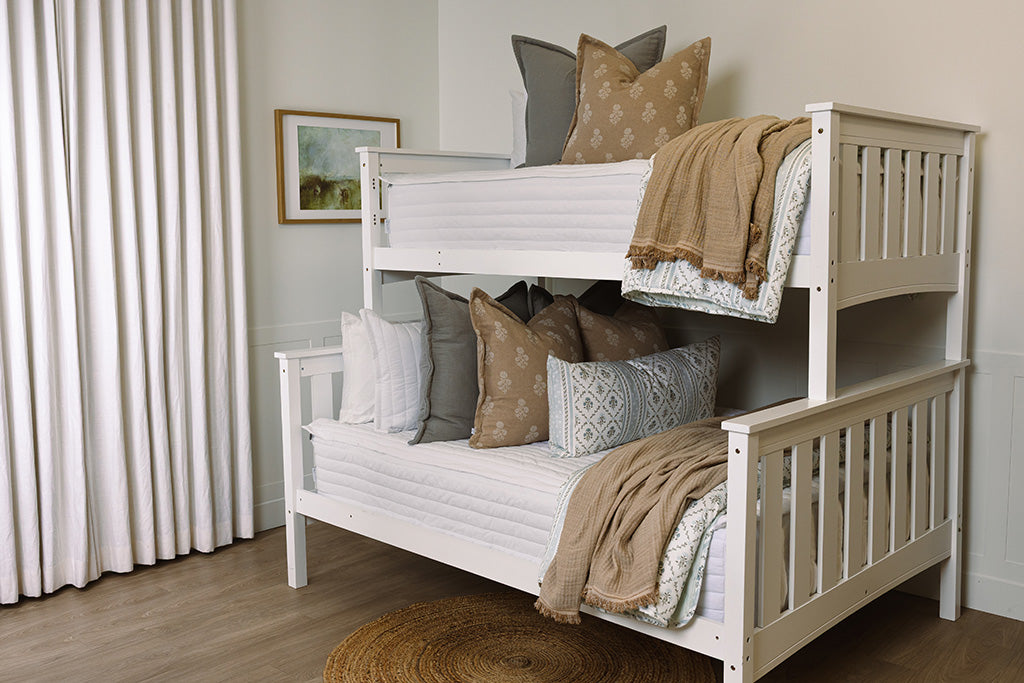A bunk bed made with tan, gray, and floral accessories.