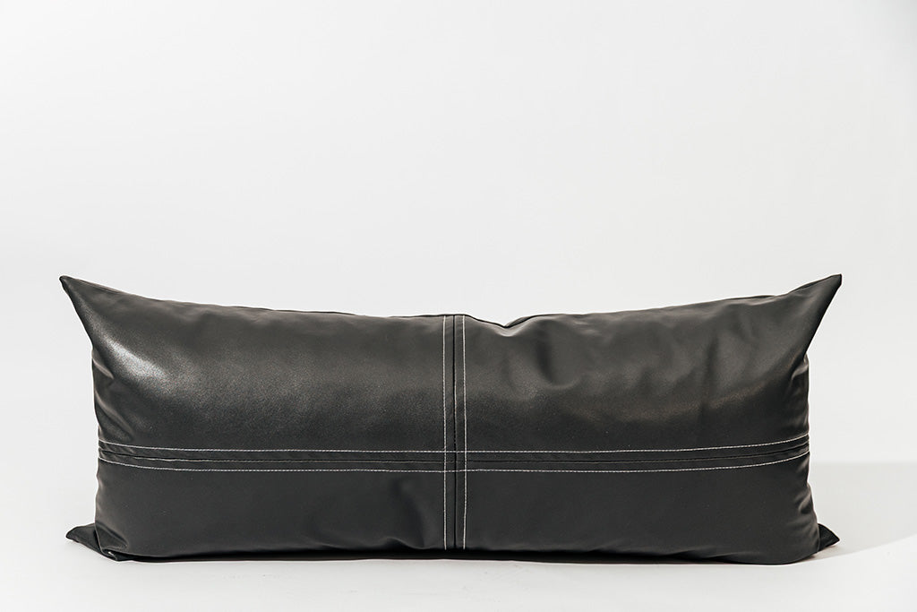 Grey leather lumbar pillow on a white backdrop.