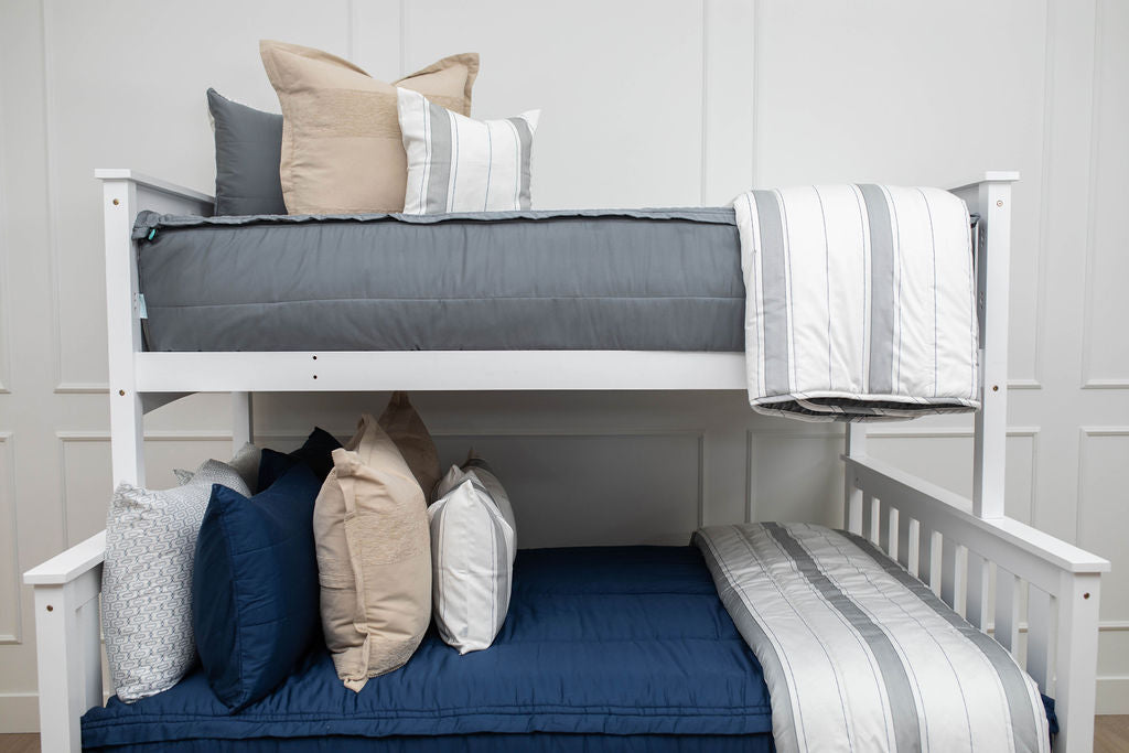 A standard bunk bed with both bunks made with navy blue zipper bedding and neutral and gray striped pillows and blankets.