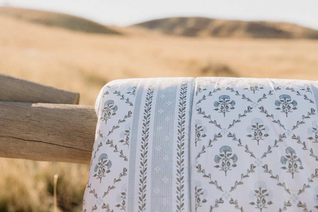 A blue floral blanket draped on a fence. 