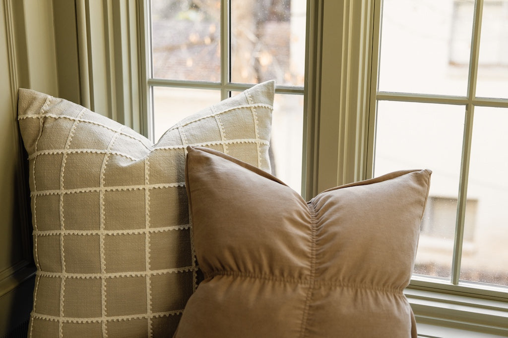Light brown medium pillow and a tan and cream embroidered stitched pillow. 