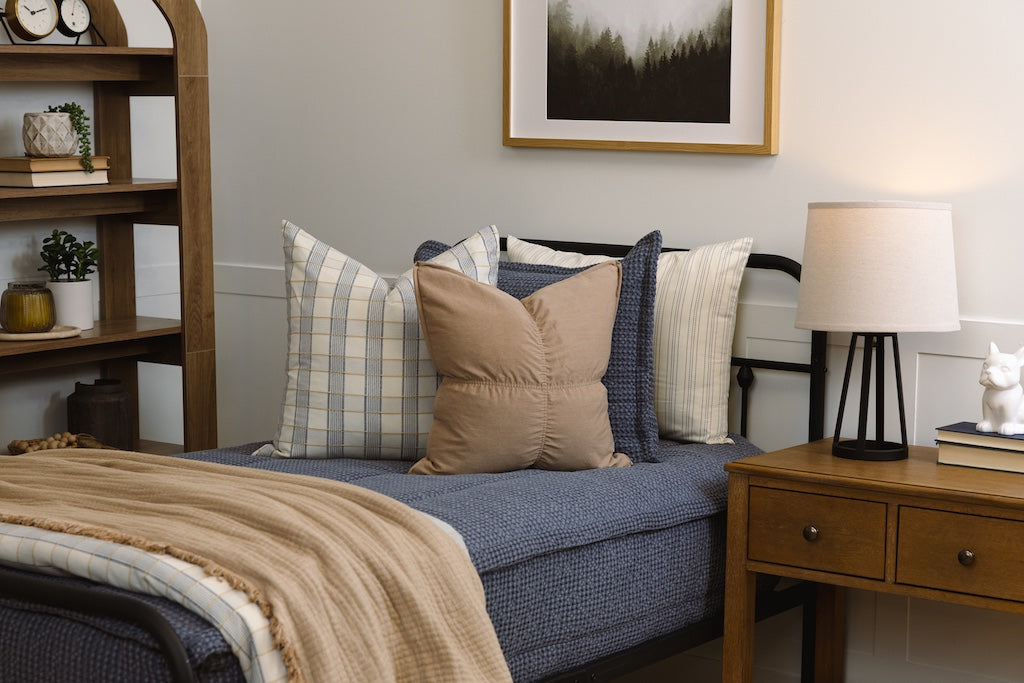 Twin bed with blue knitted zipper bedding with tan and plaid accessories.