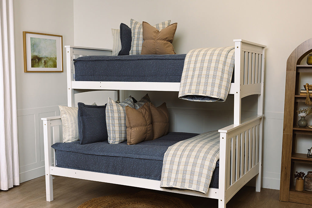 A bunk bed made with blue waffle texture zipper bedding with tan and plaid accessories.