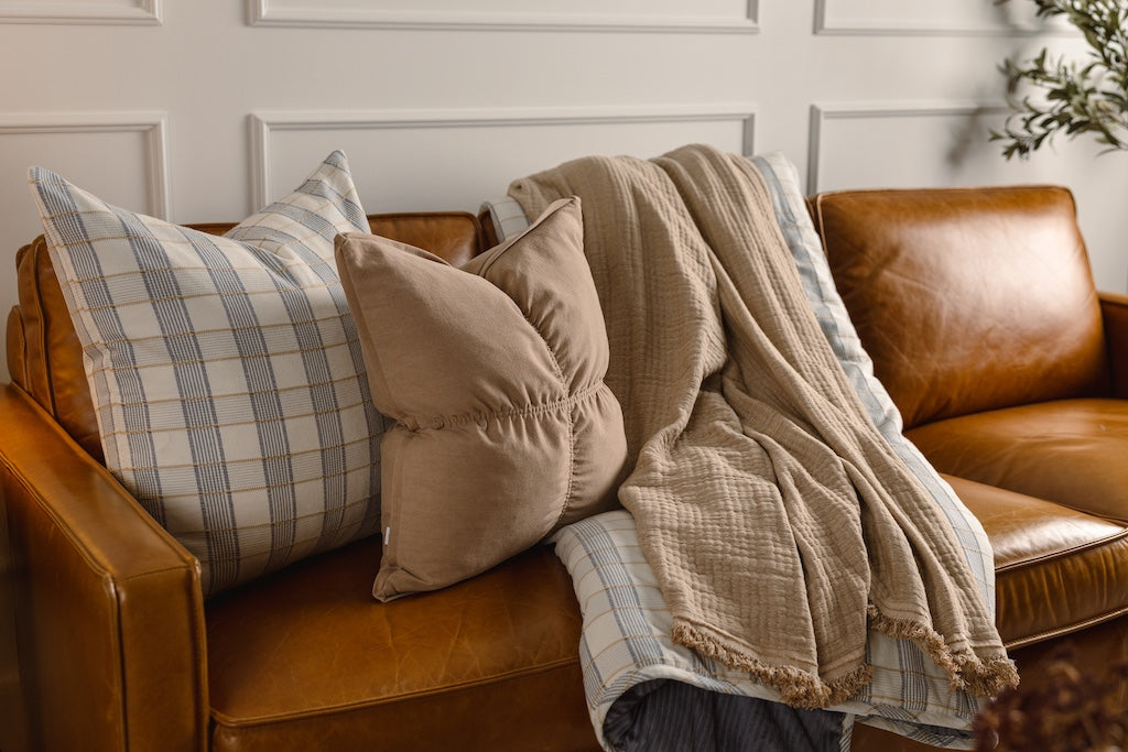 A yellow and blue plaid stitched pillow and blanket with a tan pillow and throw blanket.