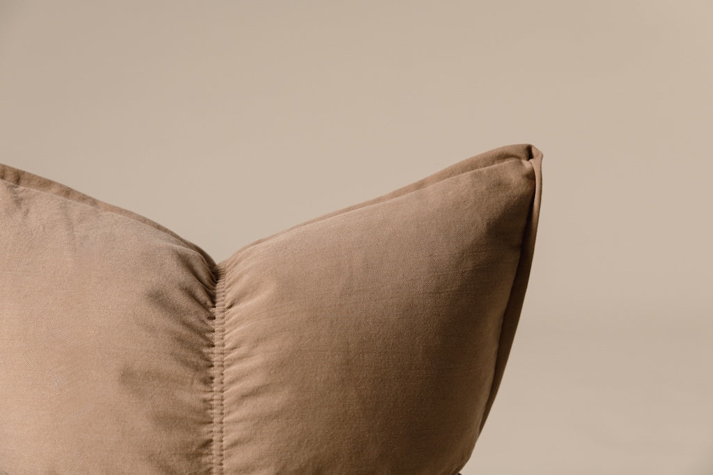 Light brown medium pillow on a cream backdrop.