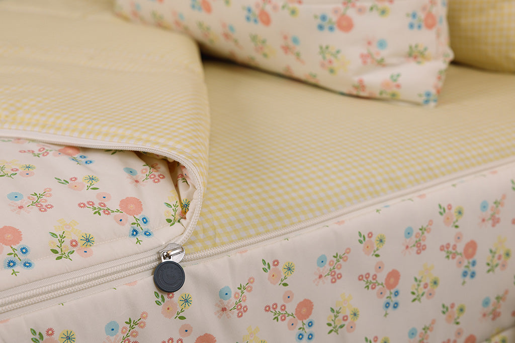A tight shot of the zipper feature on a set of yellow gingham and flower printed zipper bedding.