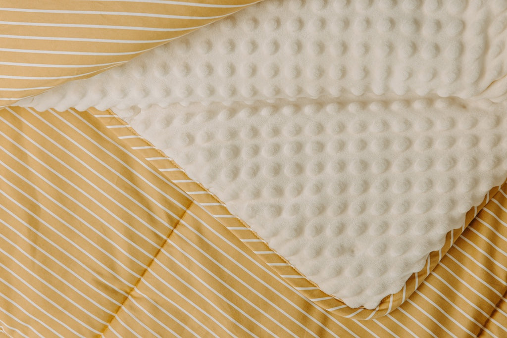 Yellow and white striped blanket with cream colored minky interior.