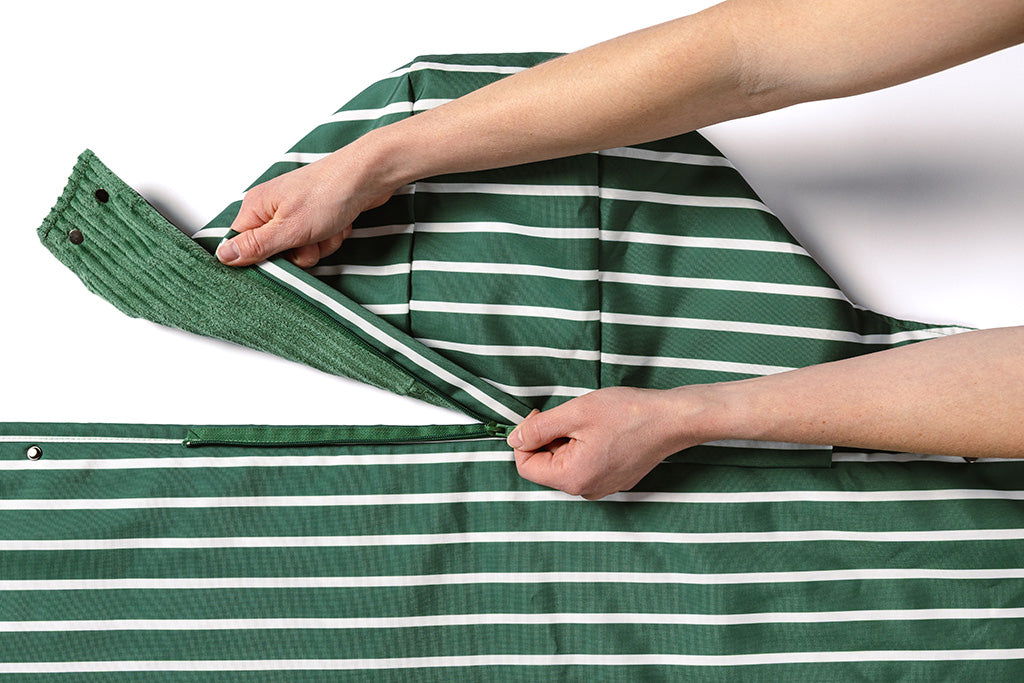 A woman showing the detachable zipping feature of the hood on the stadium blanket.