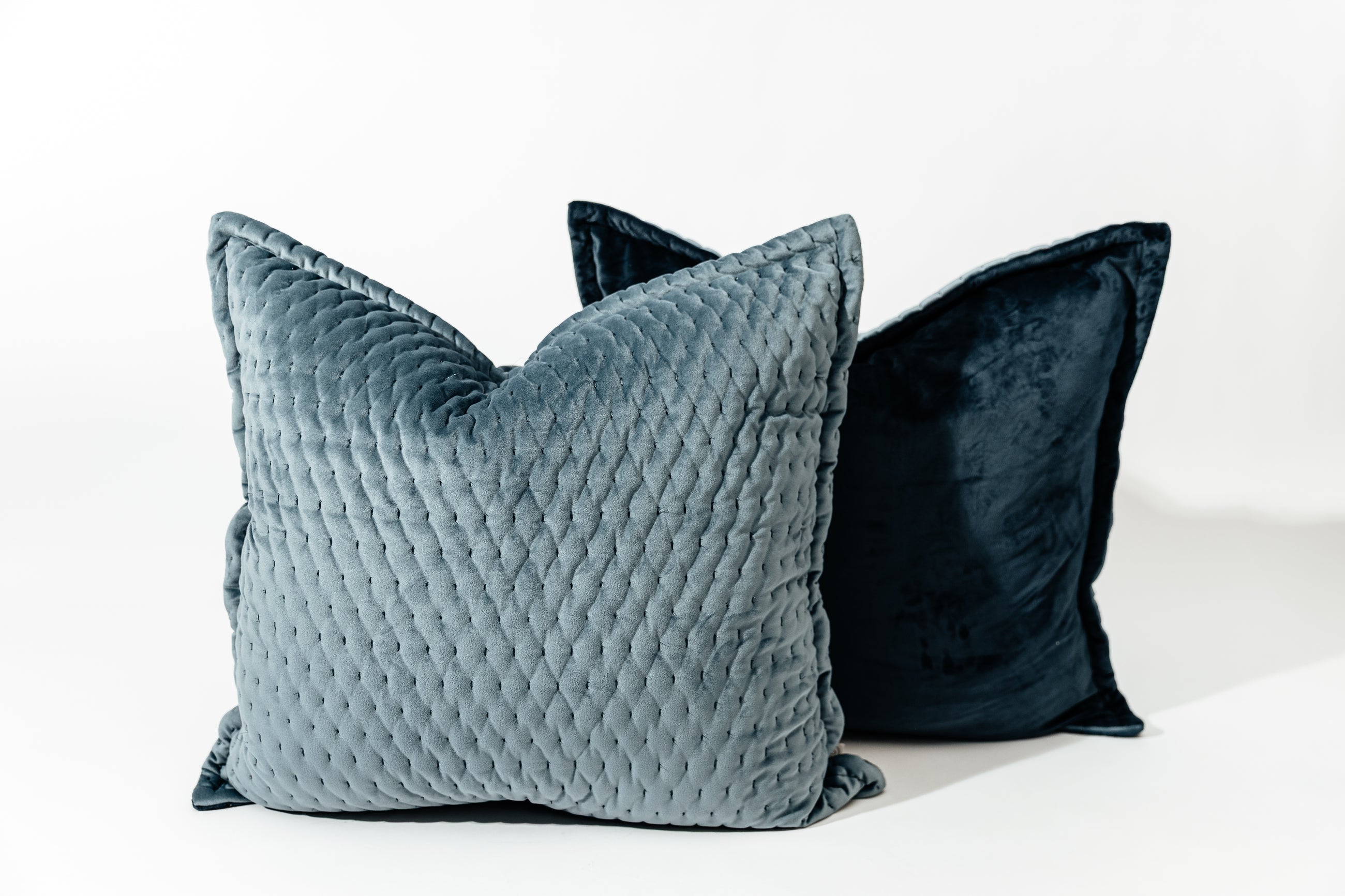 Two blue velvet euro pillows arranged on a white background.