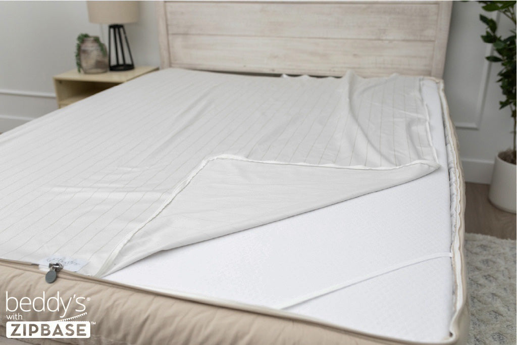 A ZipBase sheet partially unzipped and pulled back to show how it detaches from the rest of the base sheet wrapped around the sides of the mattress.