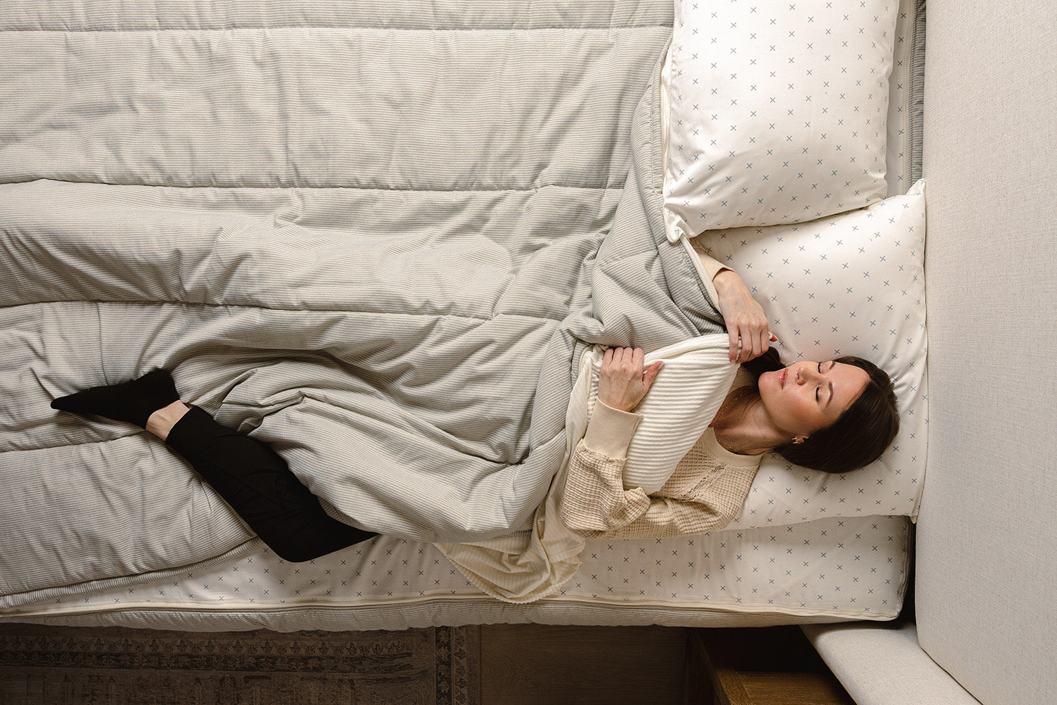 A women sleeping in her blue and white stripe zipper bedding. 