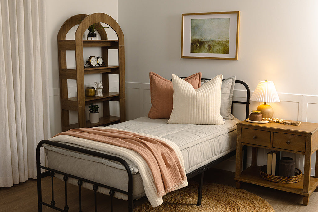 A twin bed with blue and white stripe zipper bedding with pink and cream accessories.